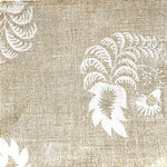 Detail of fabric in a floral paisley print in white on a tan field.