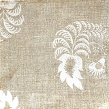 Detail of fabric in a floral paisley print in white on a tan field.