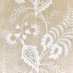 Detail of fabric in a floral trellis print in white on a tan field.