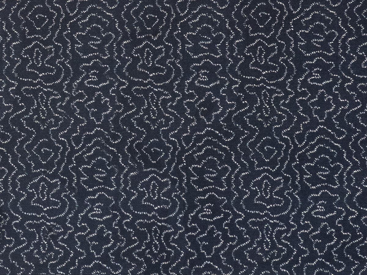 Detail of fabric in a minimalist wood grain print in white on an indigo field.