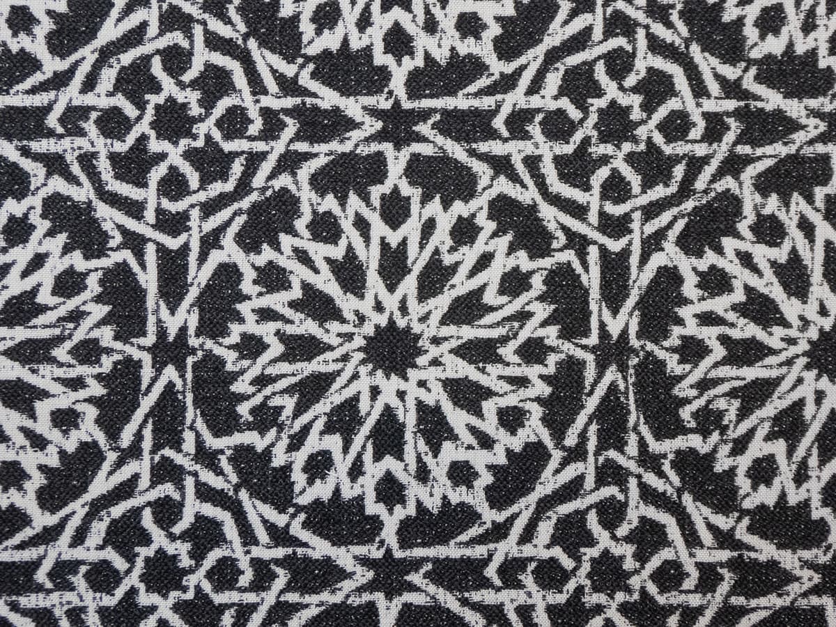 Detail of fabric in a small-scale lattice print in light gray on a charcoal field.