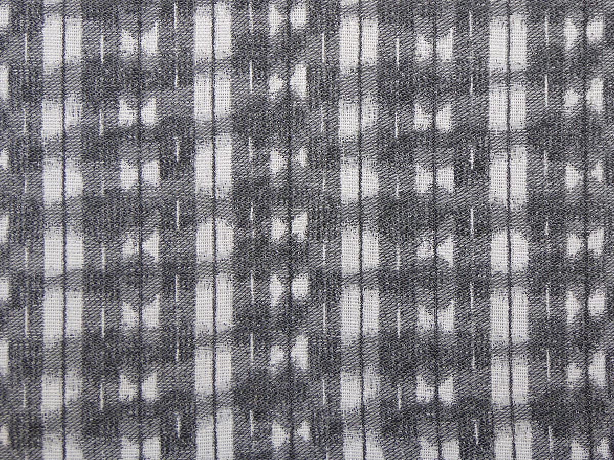 Detail of fabric in a textural shibori print in shades of charcoal on a greige field.