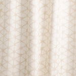 Draped fabric yardage in a painterly lattice print in tan on a cream field.