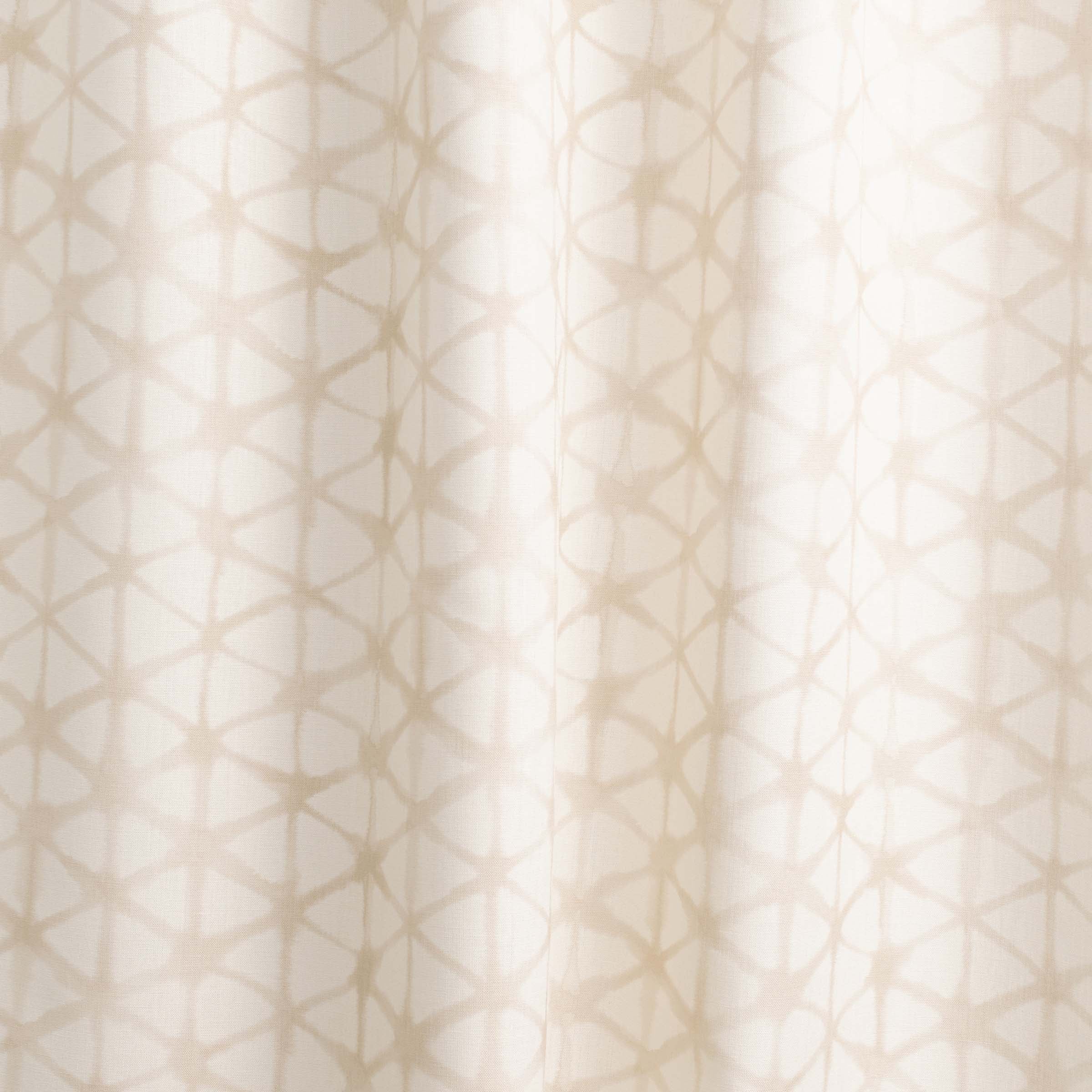 Draped fabric yardage in a painterly lattice print in tan on a cream field.