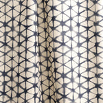 Draped fabric yardage in a painterly lattice print in indigo on a tan field.