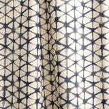 Draped fabric yardage in a painterly lattice print in indigo on a tan field.