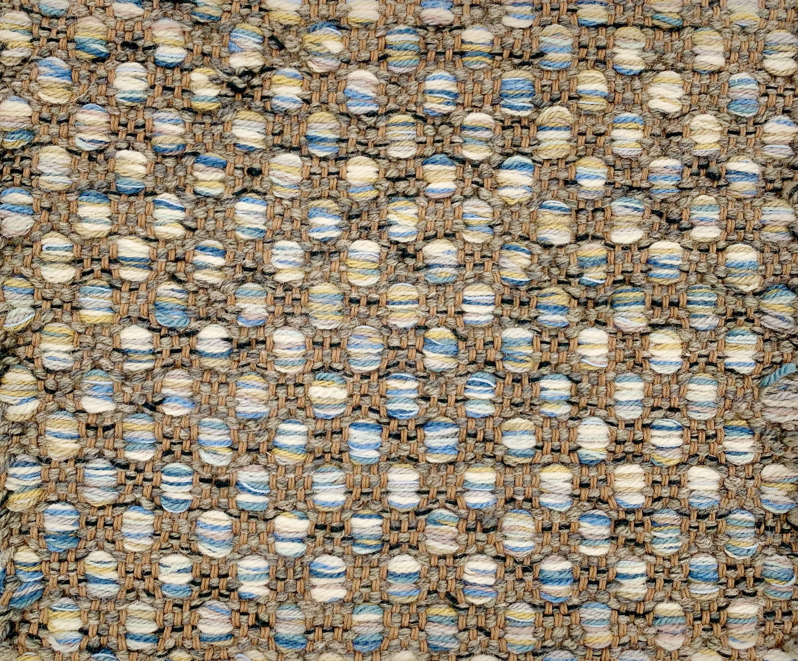 Handwoven rug detail in a textural design in blue, tan, cream