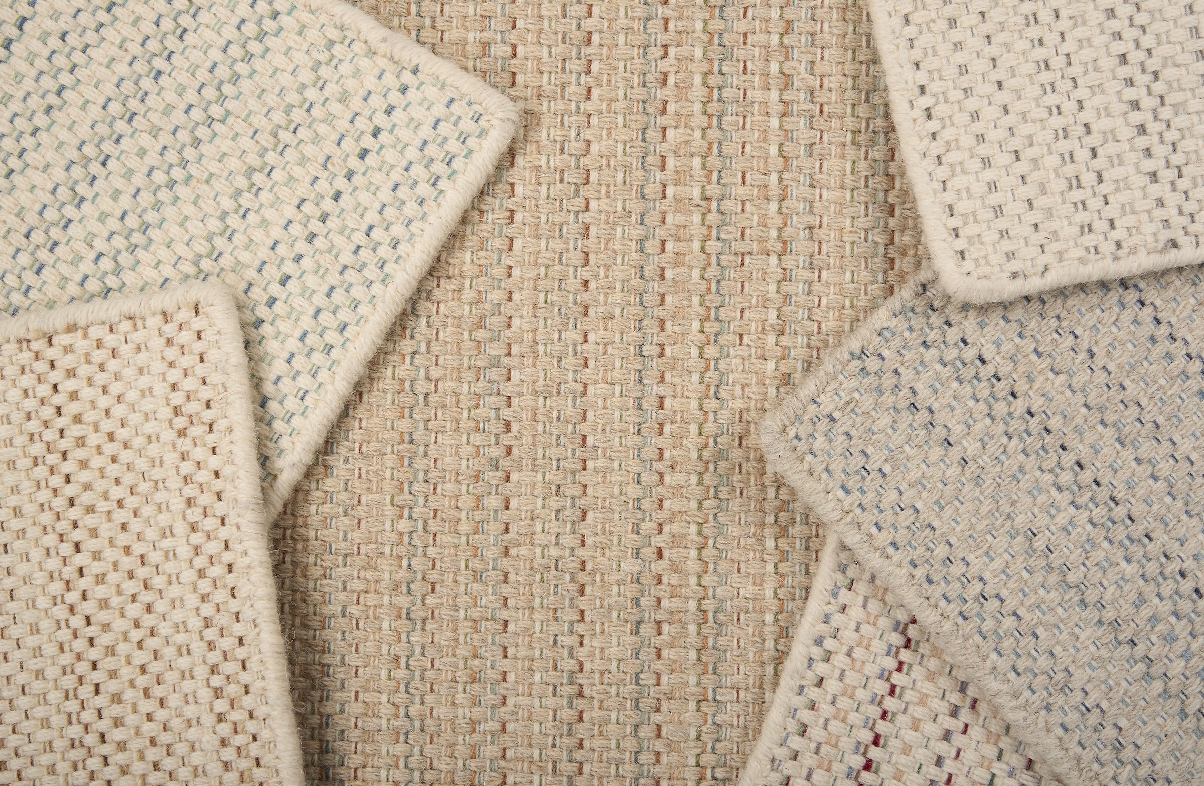 A scattered pile of broadloom carpets in a textural stripe in a range of colors.