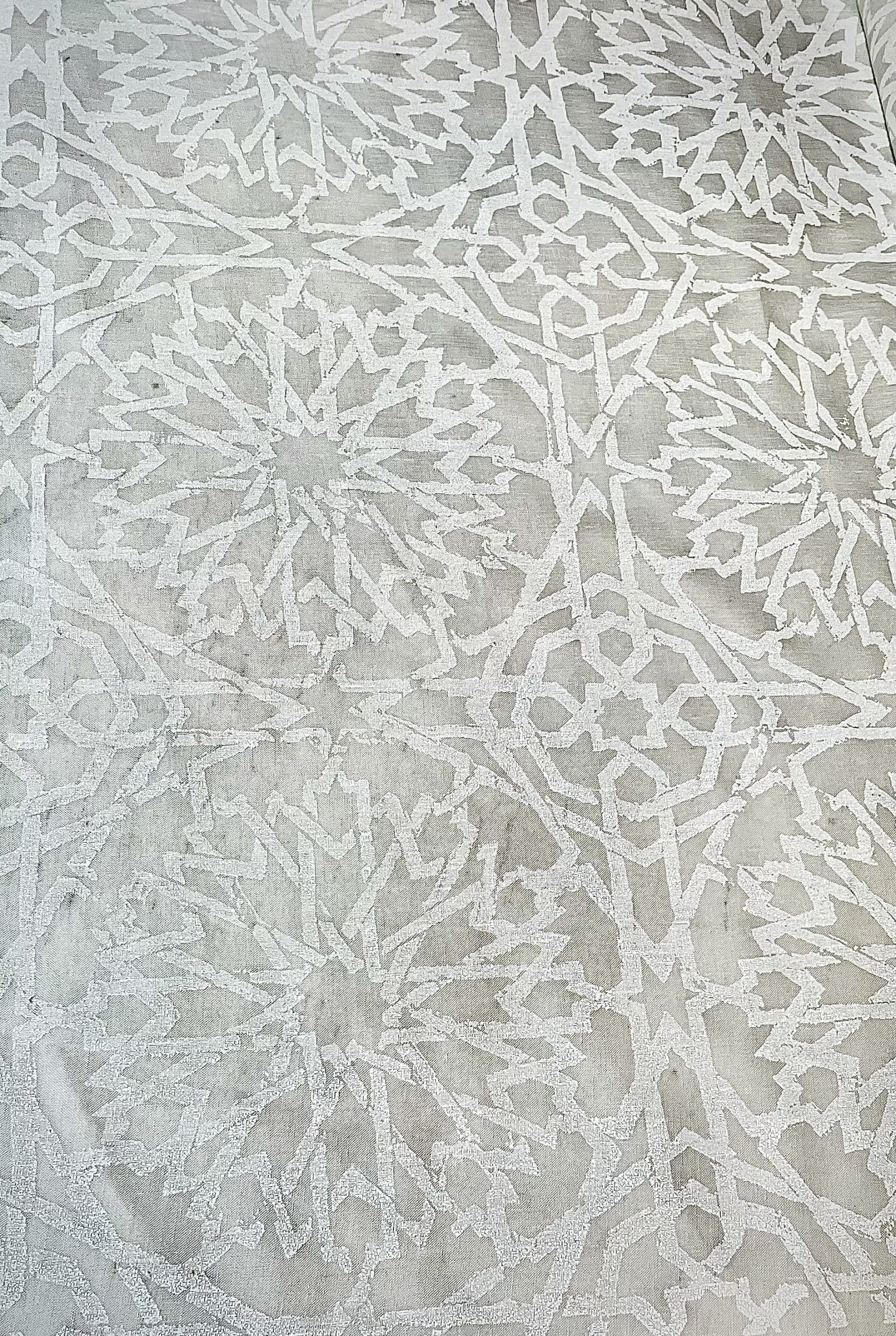 Detail of sheer fabric in a small-scale lattice print in light gray on a gray field.