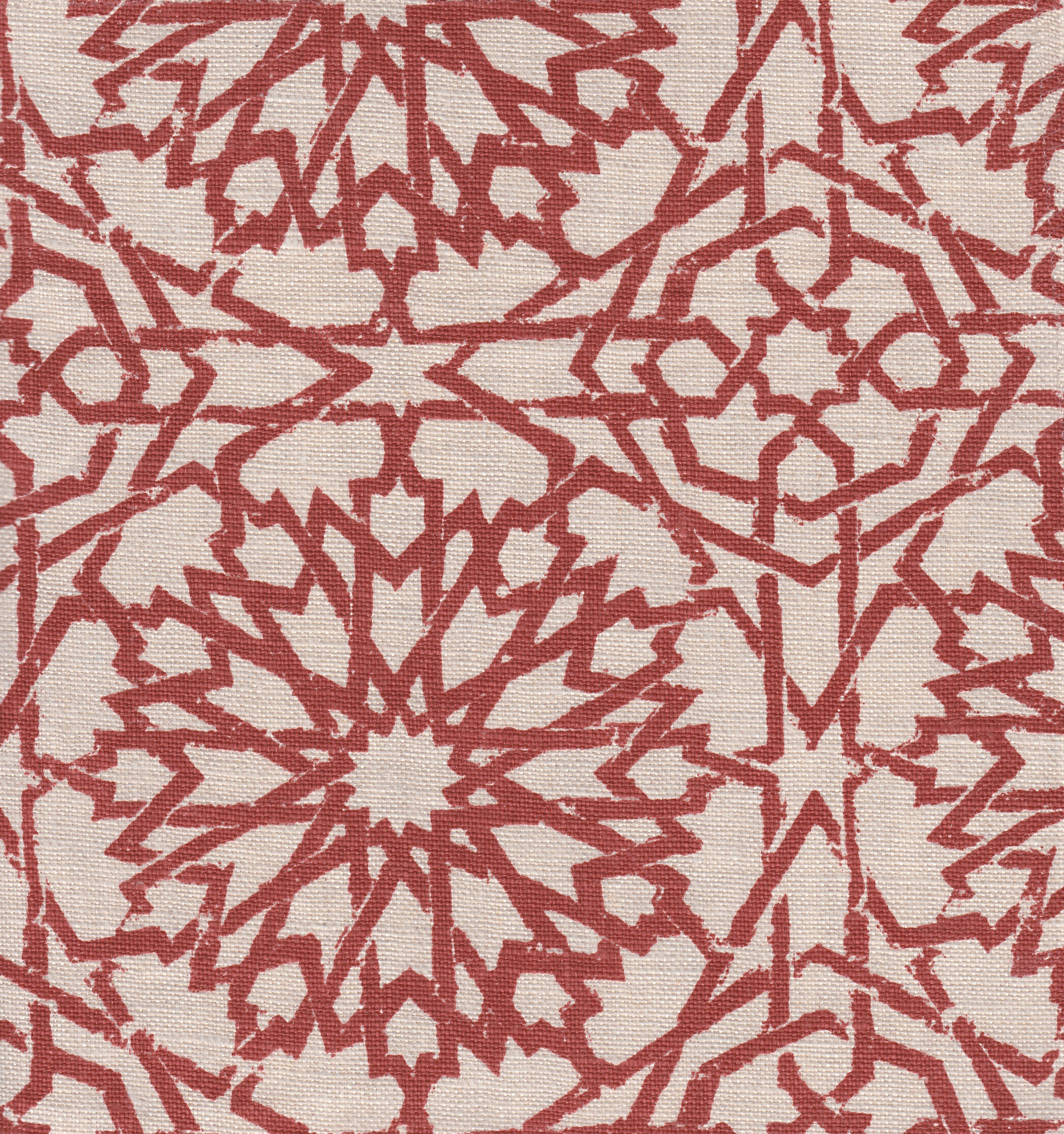 Detail of fabric in a small-scale lattice print in red on a cream field.