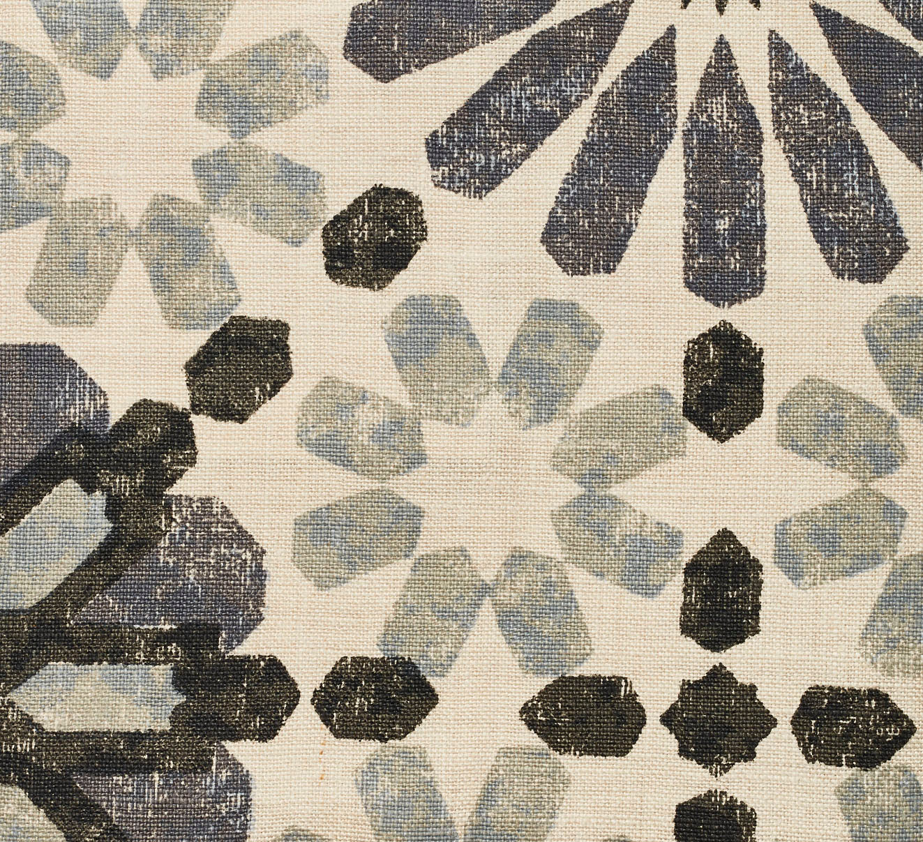 Detail of fabric in a geometric lattice print in shades of black, blue and gray on a cream field.