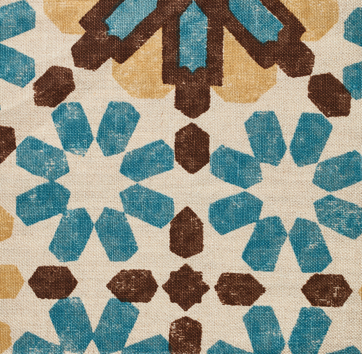 Detail of fabric in a geometric lattice print in shades of blue, brown and yellow on a cream field.