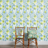 An armchair stands in front of a wall papered in a painterly floral print in white, blue and navy.