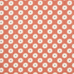 Detail of fabric in a repeating blossom print in white on a burnt orange field.