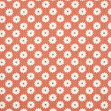 Detail of fabric in a repeating blossom print in white on a burnt orange field.