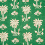 Detail of fabric in a playful palm tree print in white and red on a green field.