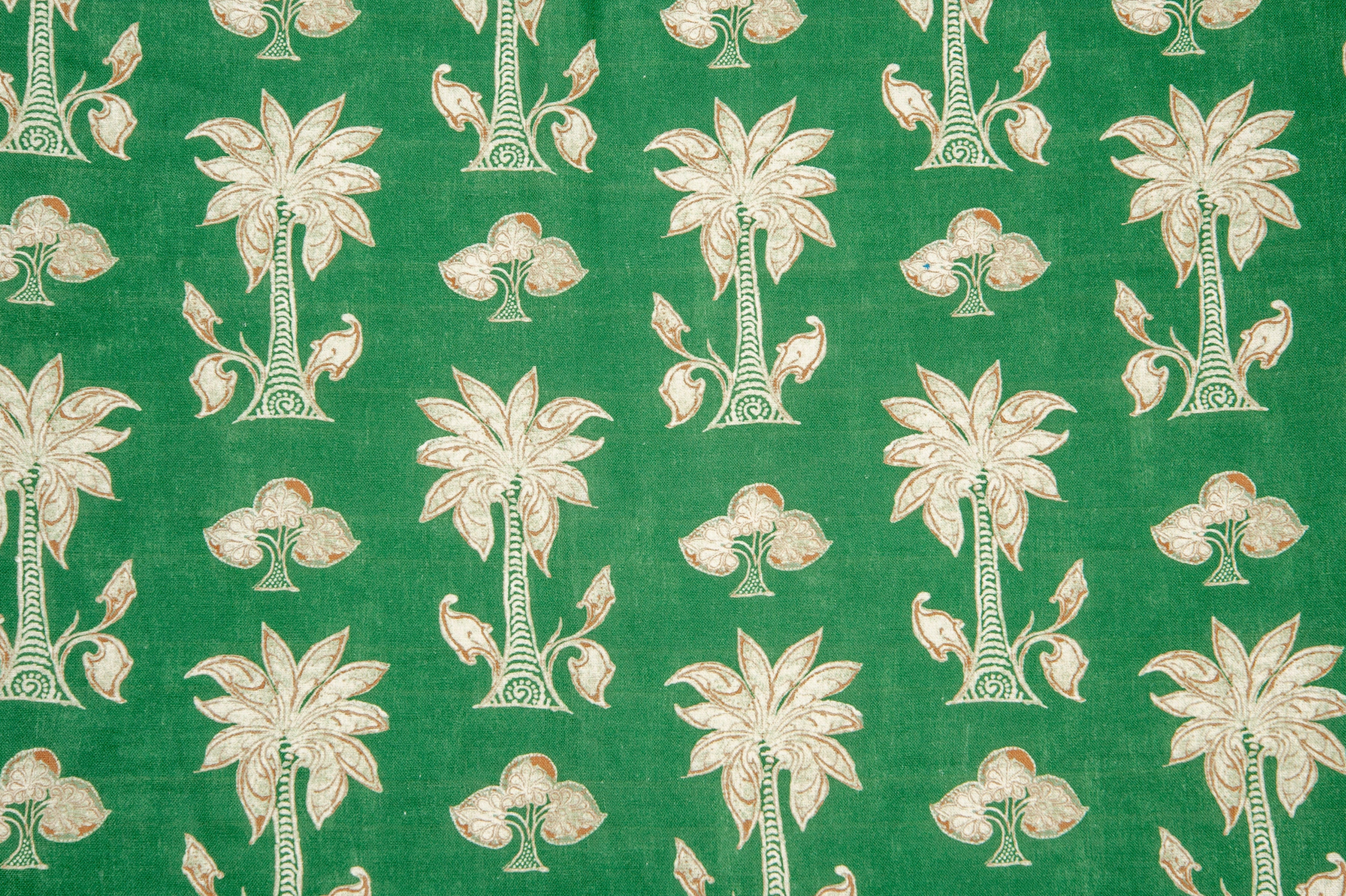 Detail of fabric in a playful palm tree print in white and red on a green field.