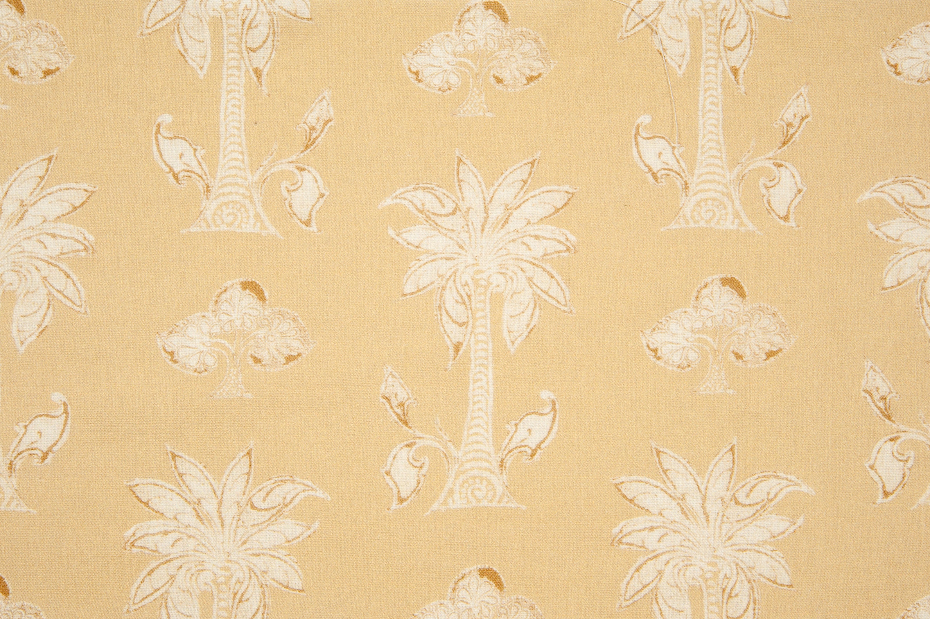 Detail of fabric in a playful palm tree print in tan and white on a light yellow field.