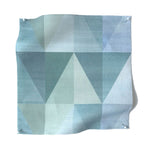 Square fabric swatch in a linear triangle print in shades of tan, navy and blue.