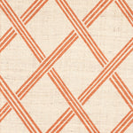 Detail of fabric in a diamond lattice print in orange on a cream field.