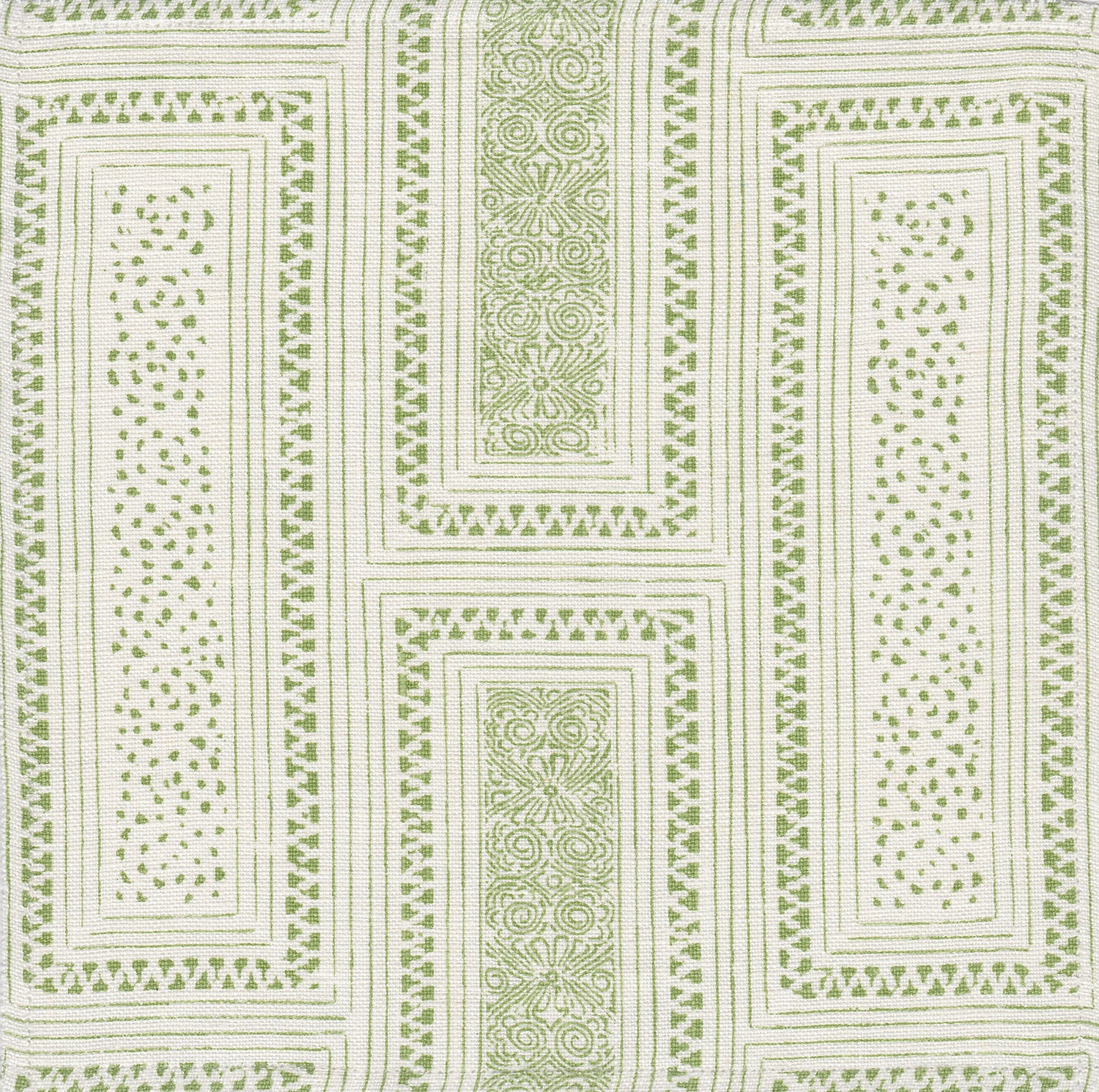 Detail of fabric in a complex interlocking geometric print in green on a cream field.