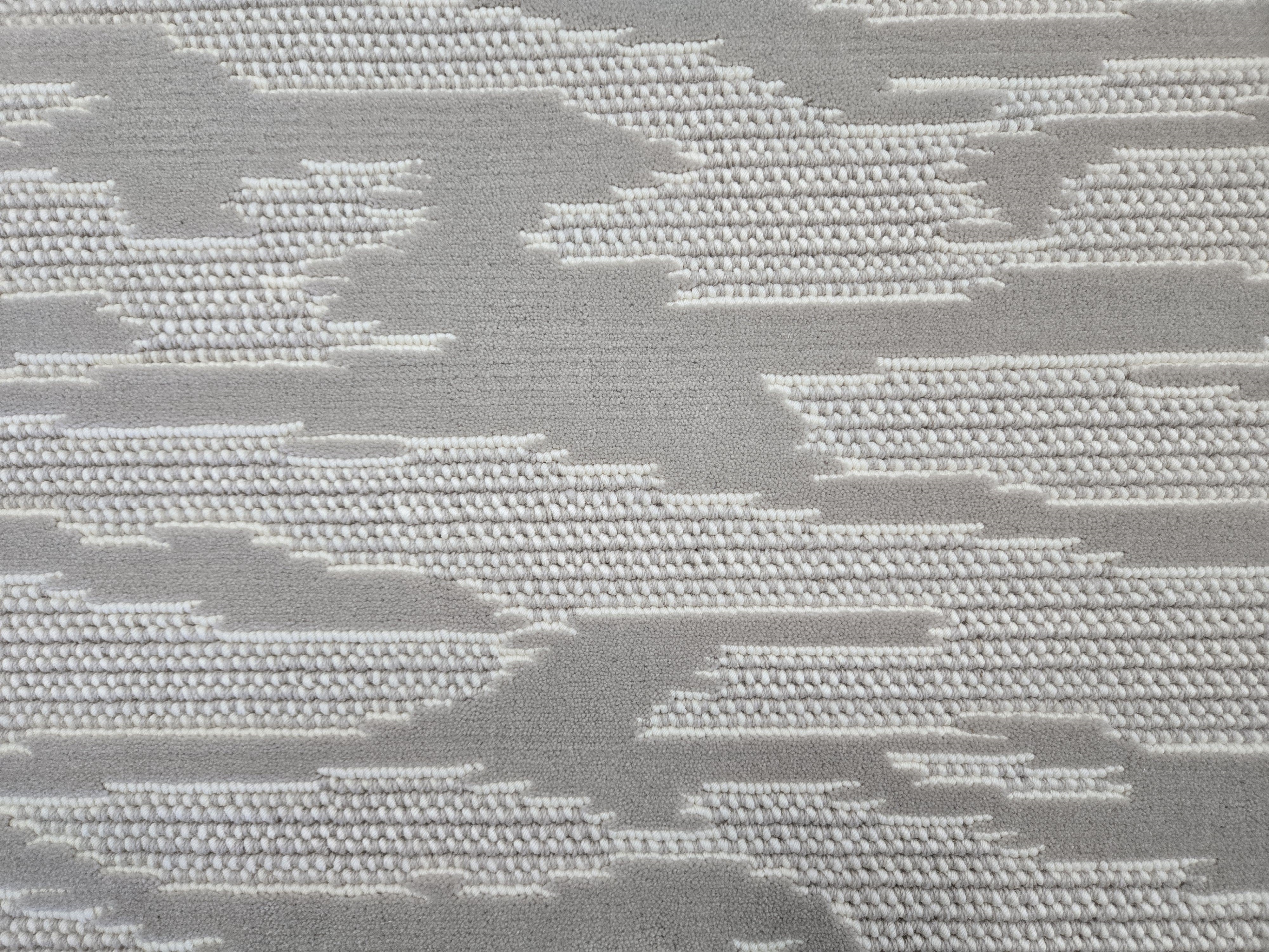 Broadloom carpet detail in an abstract cloud design in ivory and toner grey.