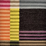 Detail of a flatwoven rug in a graphic broken stripe pattern in bright colors- orange, lime, pink, black, grey brown and green.