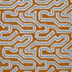 Detail of fabric in a dense meandering print in white, blue and gray on a burnt orange field.