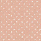 Detail of fabric in a repeating leaf print in cream on a light pink field.