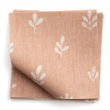 A stack of fabric swatches in a repeating leaf print in cream on a light pink field.