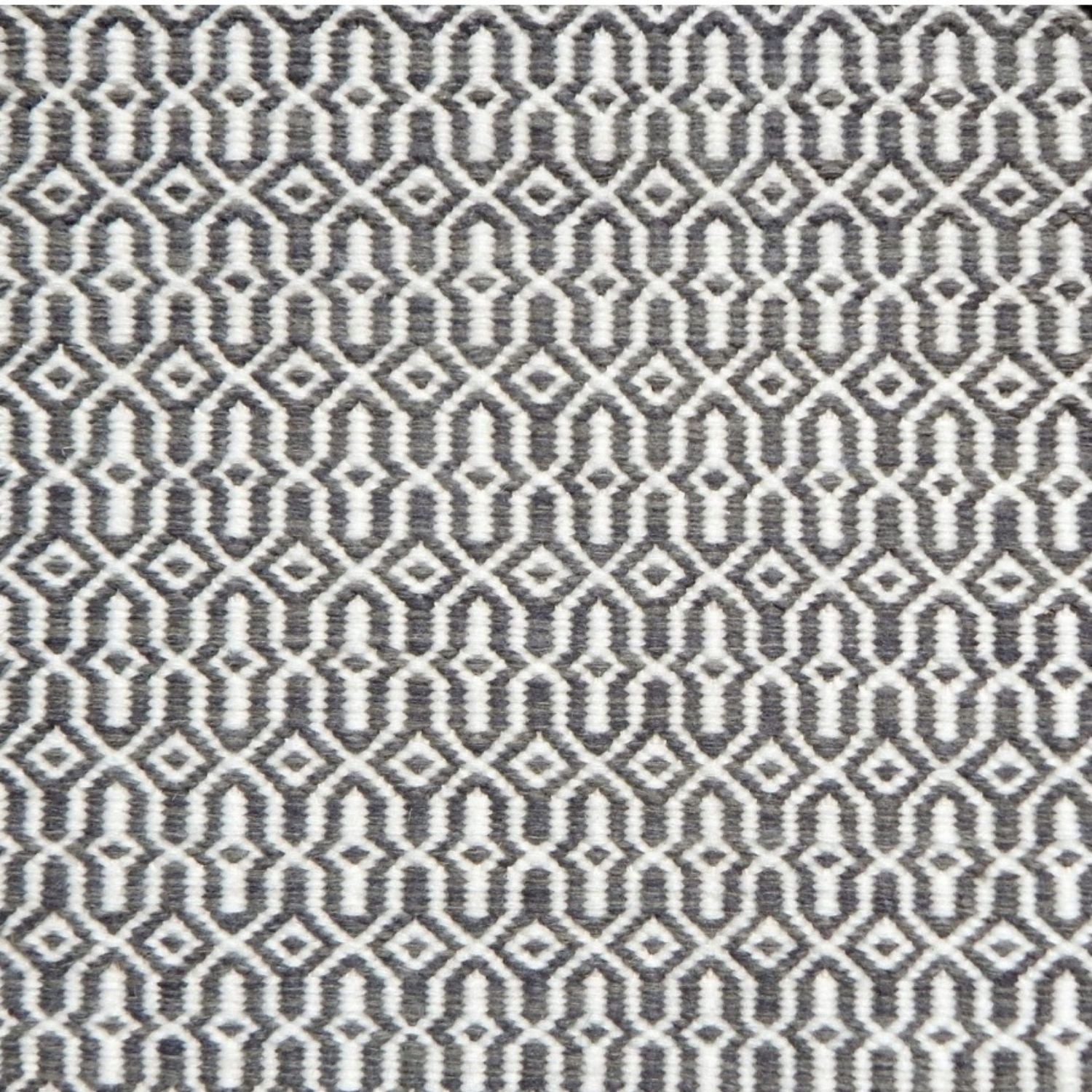 A rug with an overall geometric pattern in dark blue grey and ivory.