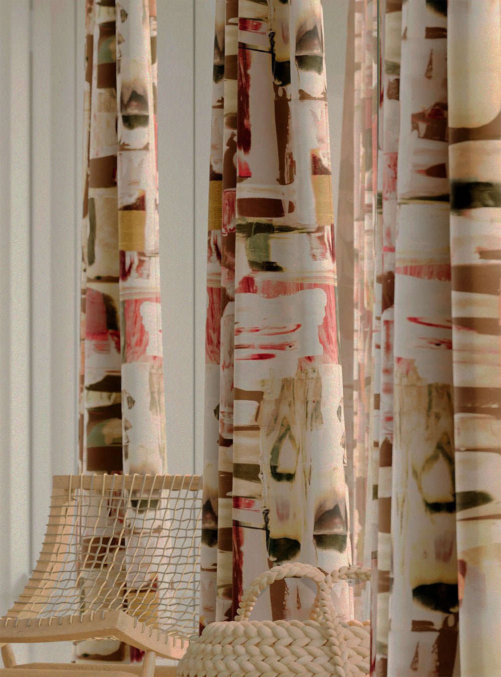 Close-up of a row of curtains in an abstract layered paint blotch print in shades of olive, cream and pink.