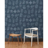 A chair and stool in front of a wall papered in a pattern of white hand-drawn illustrations of New York City landmarks on a navy background.