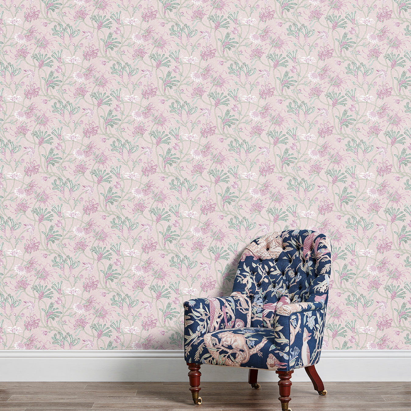 An armchair stands in front of a wall papered in a painterly floral print in white, pink and green.