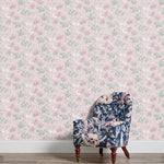 An armchair stands in front of a wall papered in a painterly floral print in white, pink and green.