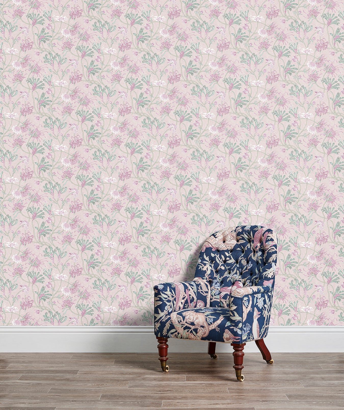 An armchair stands in front of a wall papered in a painterly floral print in white, pink and green.