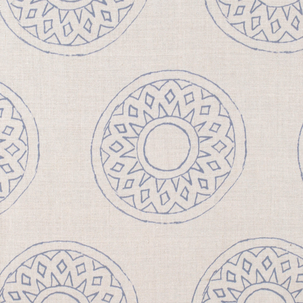 Detail of fabric in a repeating circular geometric print in blue on a cream field.