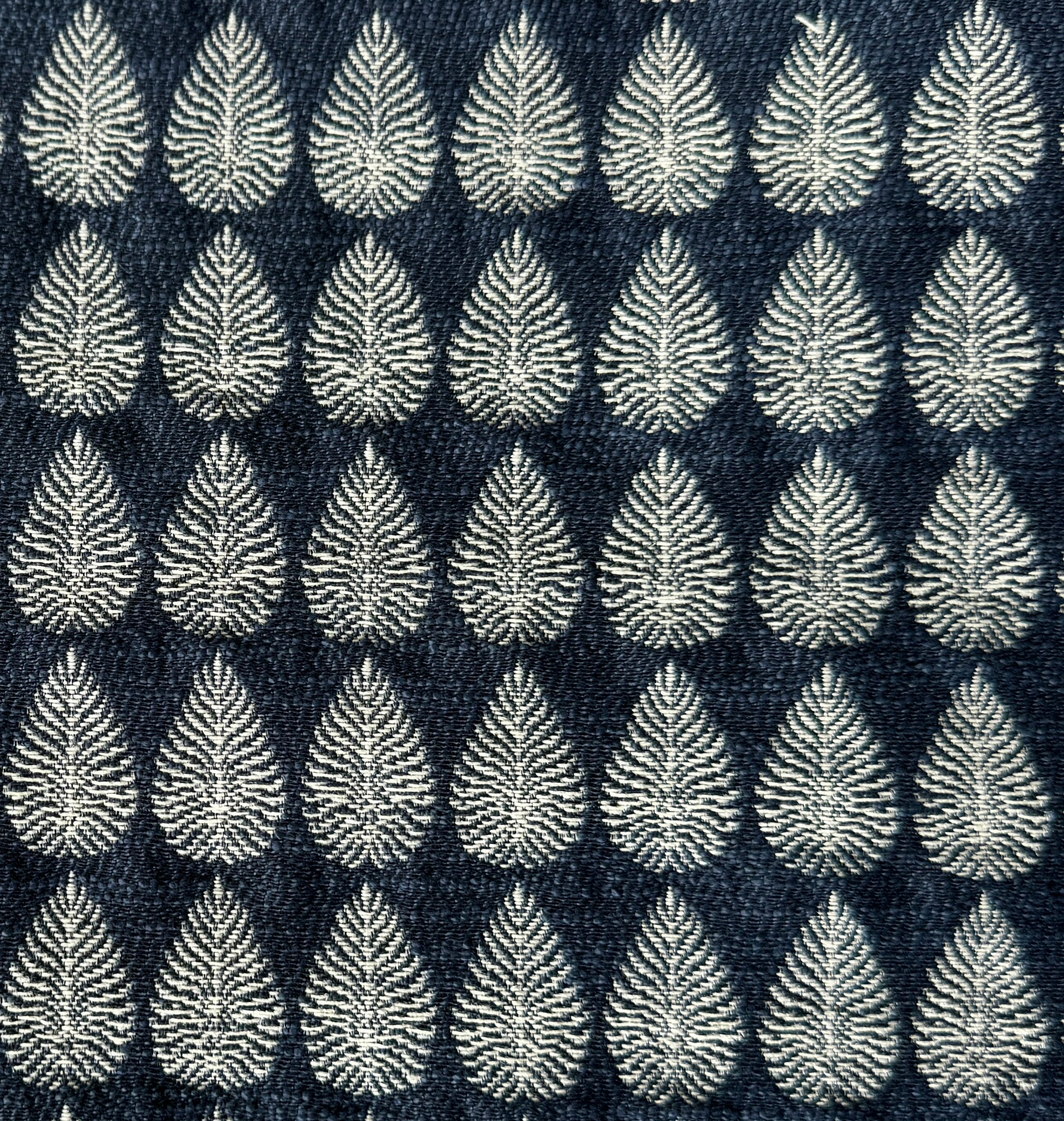 Detail of fabric woven in a repeating leaf print in shades of navy and white.