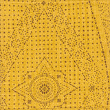 Detail of fabric in a dotted geometric print in brown on a yellow field.