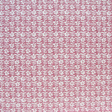 Detail of fabric in a floral grid print in white and red on a pink field.