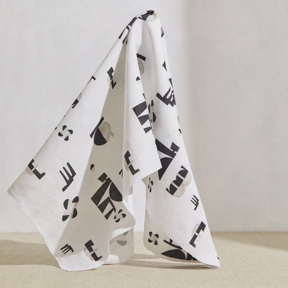 A large piece of draped fabric in an abstract geometric print in charcoal and cream on a white field.