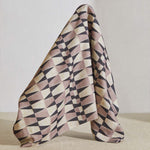 A large piece of draped fabric in a striped triangle print in shades of purple and cream.