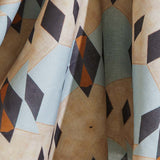 Draped fabric yardage in a striped triangle print in shades of tan, blue, navy and cream.