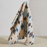 A large piece of draped fabric in a striped triangle print in shades of tan, blue, navy and cream.