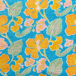 Detail of fabric in a flower and leaf print in shades of orange, pink and green on a blue field.