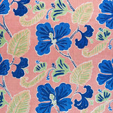 Detail of fabric in a flower and leaf print in shades of navy and green on a pink field.