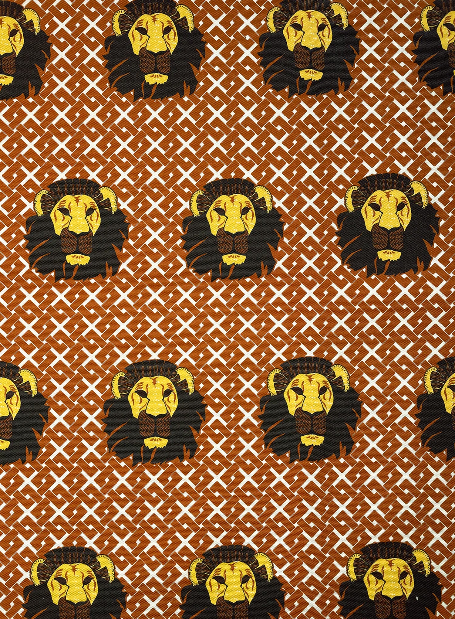 Detail of fabric in a repeating lion face print on a geometric field in shades of red, brown and yellow.