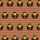 Detail of wallpaper in a repeating lion face print on a geometric field in shades of red, brown and yellow.