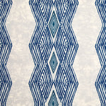 Detail of fabric in an intricate diamond stripe print in blue and navy on a cream field.