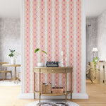 A maximalist living space with an accent wall papered in an intricate diamond stripe print in pink, orange and cream.